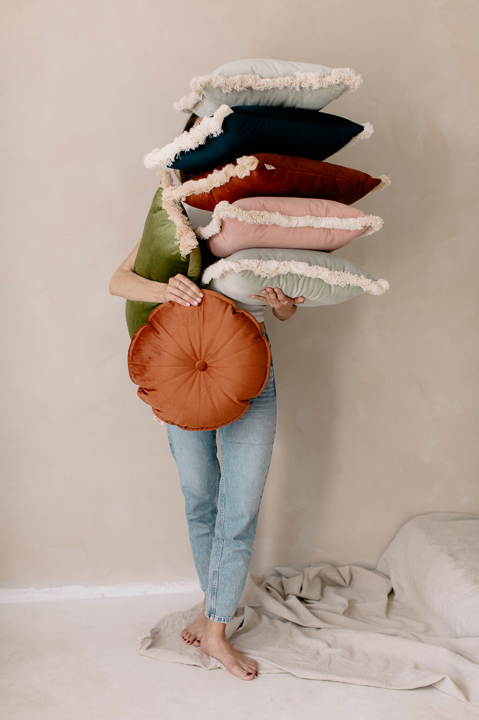 a girl holding set of decorative velvet cushions