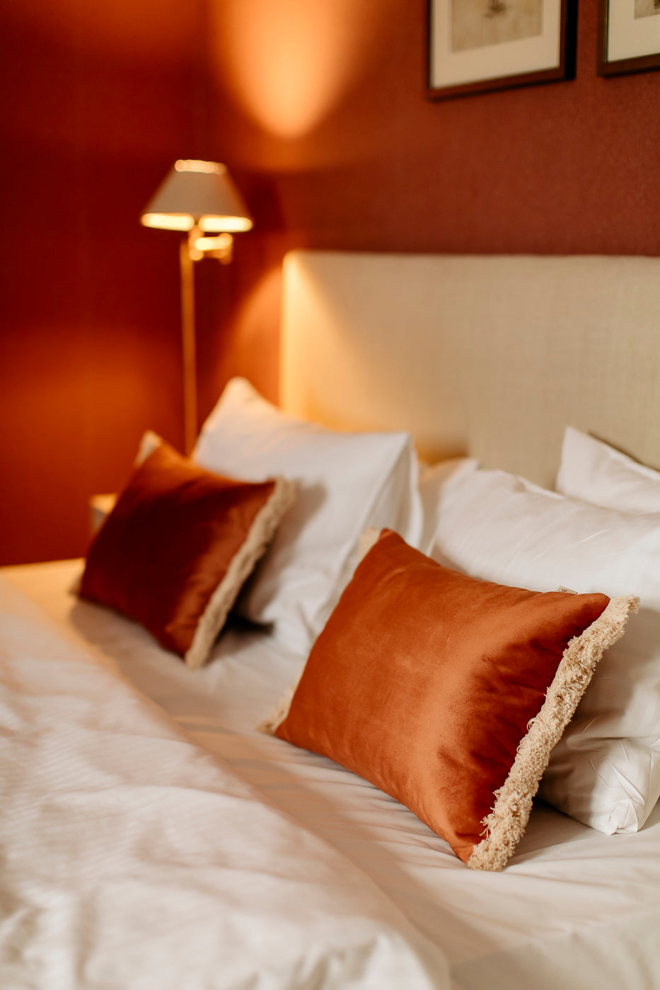 two orange pillows on white bed