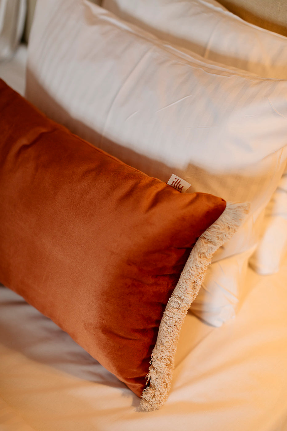 orange pillow on a hotel bed
