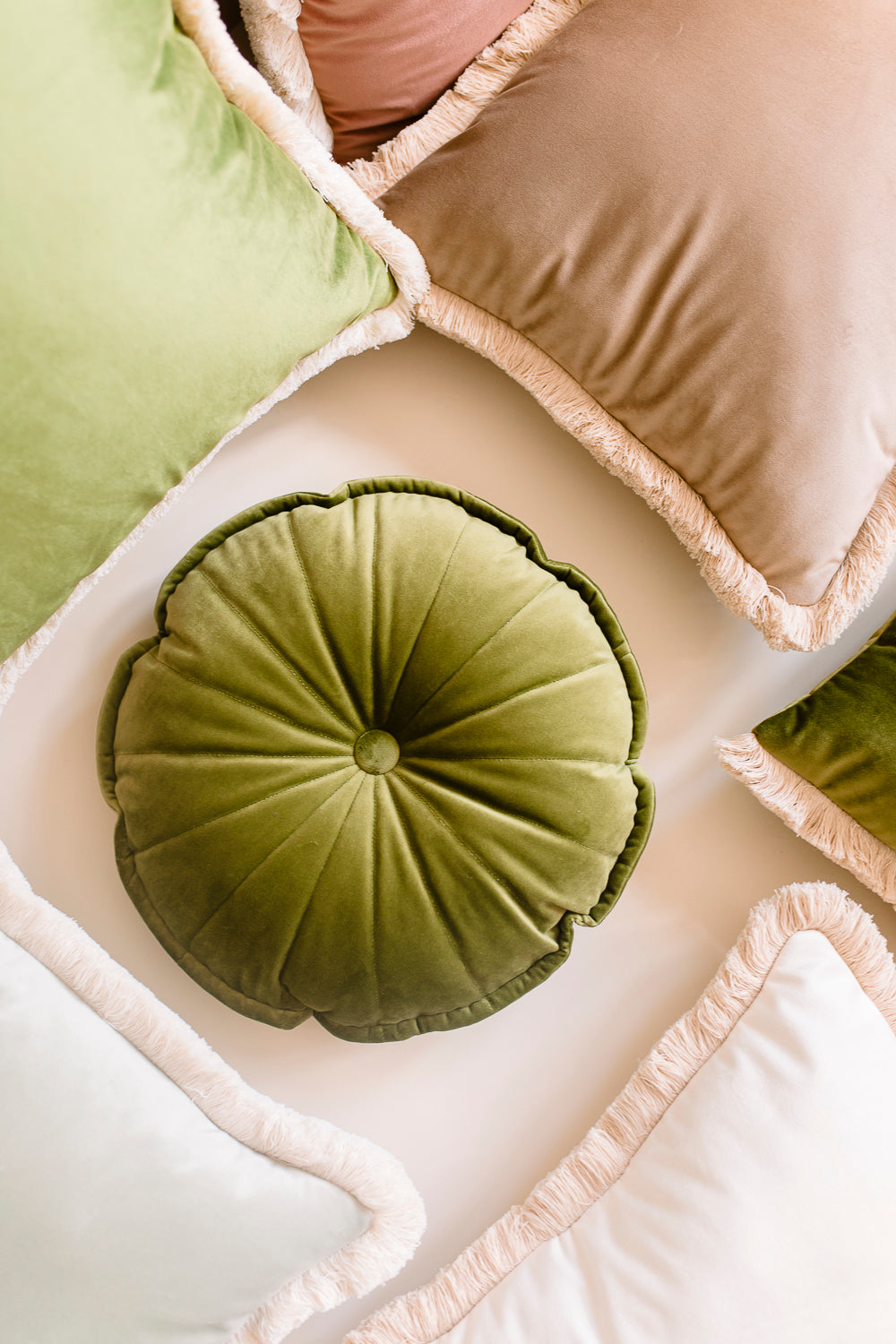 round warm green cushion and set of decorative pastel velvet pillows 